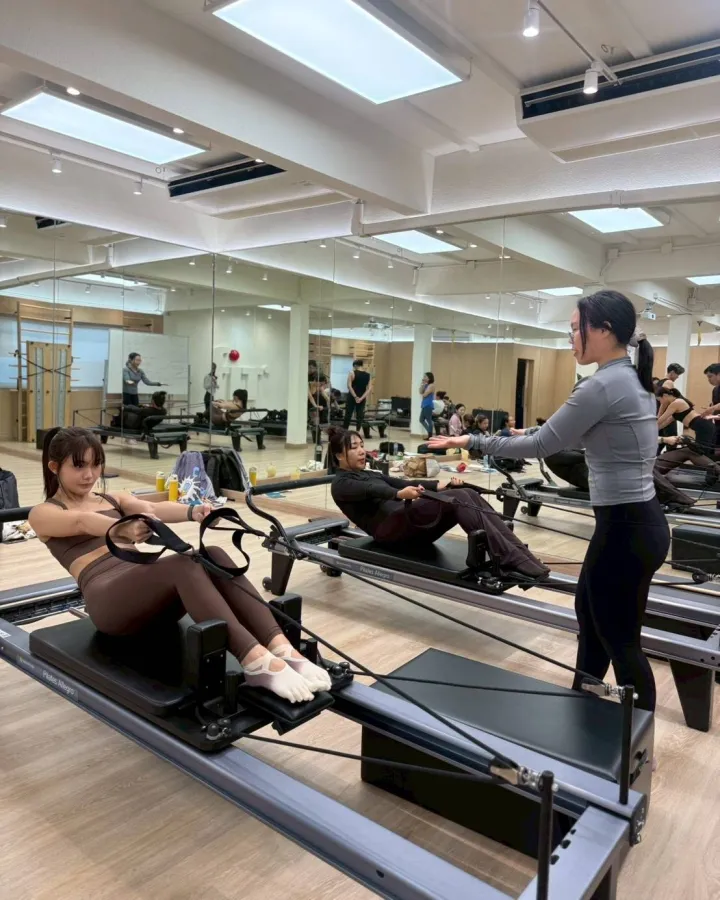 Papawadee coaching a client through a rowing exercise on the reformer